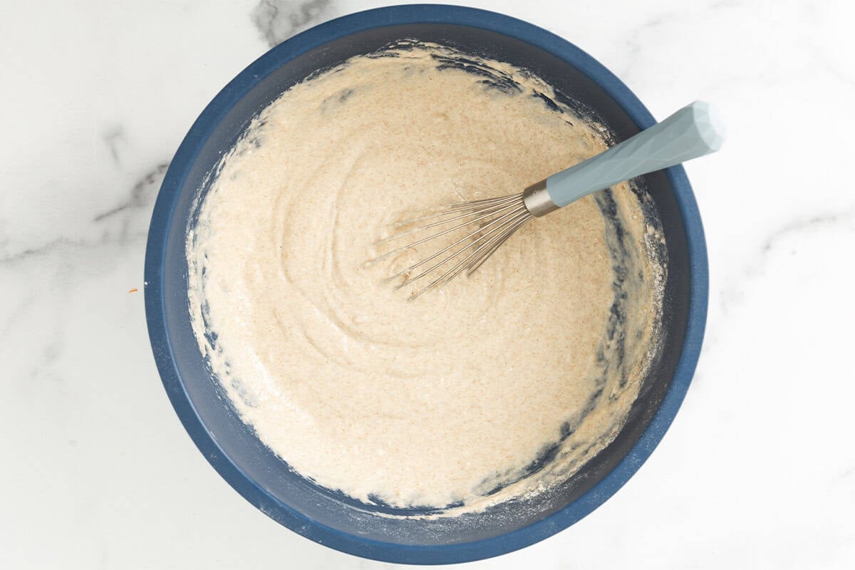 Batter for pancakes without eggs in blue bowl.