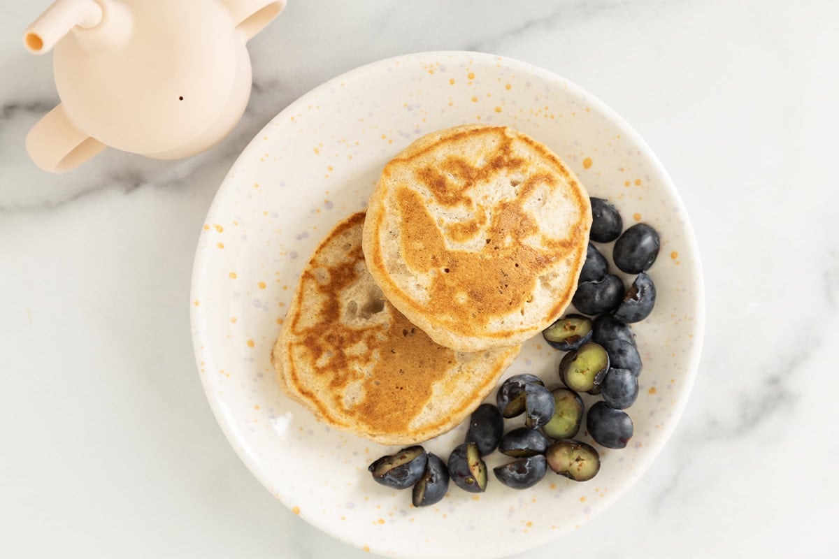 Pancakes without eggs on white plate with blueberries.
