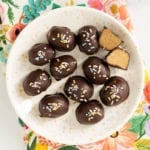 Peanut butter eggs on white plate with one cut open.