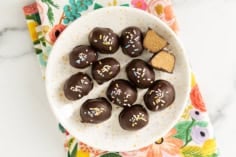 Peanut butter eggs on white plate with one cut open.