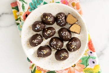 Peanut butter eggs on white plate with one cut open.