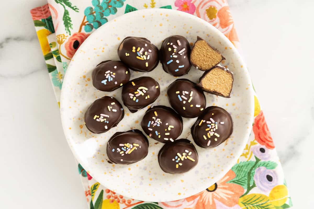 Peanut butter eggs on white plate with one cut open.