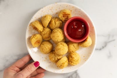 Quinoa bites on white plate with ketchup.