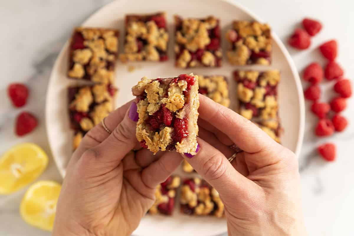 Hands holding raspberry oatmeal bar.