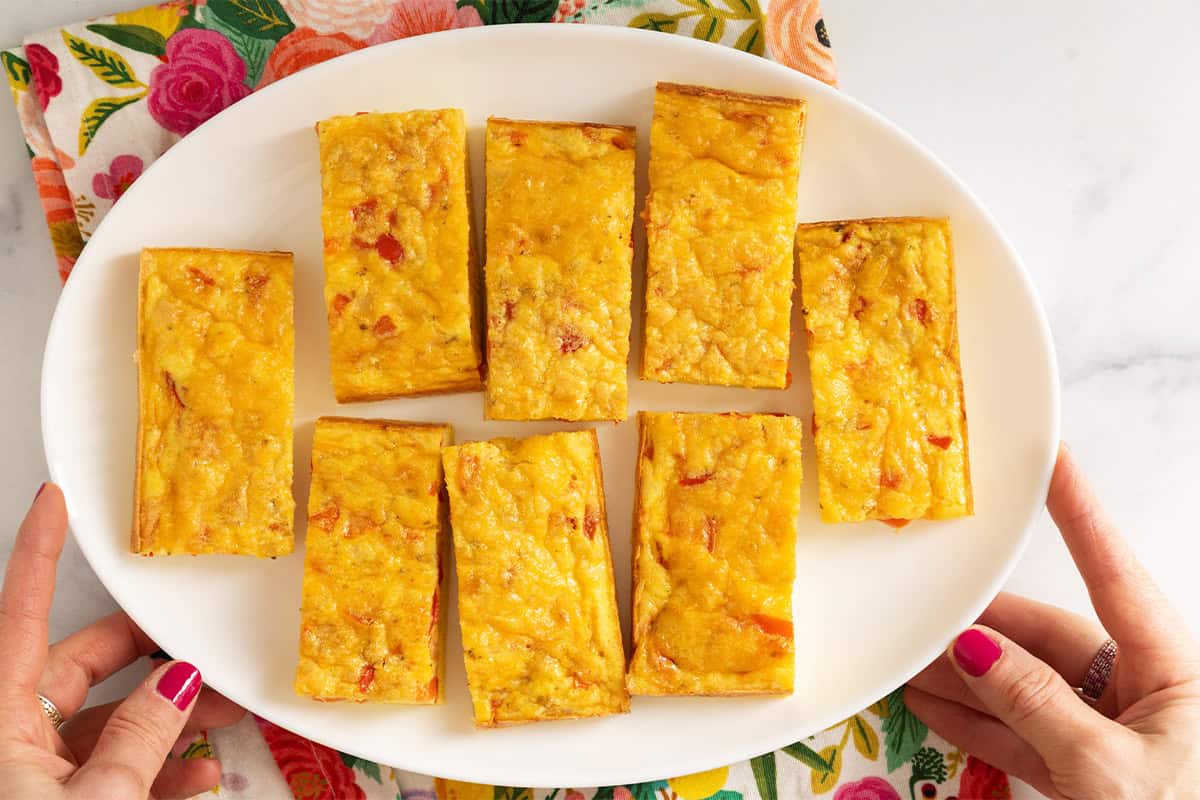 Vegetable egg bake cut into squares on white plate.