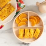 Vegetable egg bake on two plates with oranges.