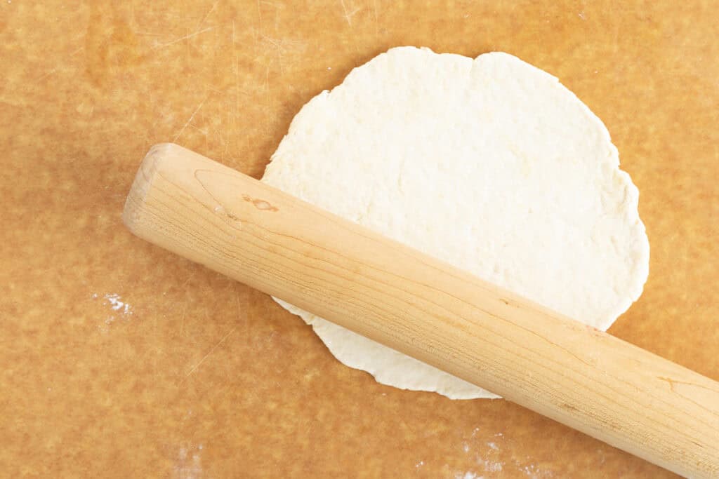 rolling out baby pizza dough on cutting board.