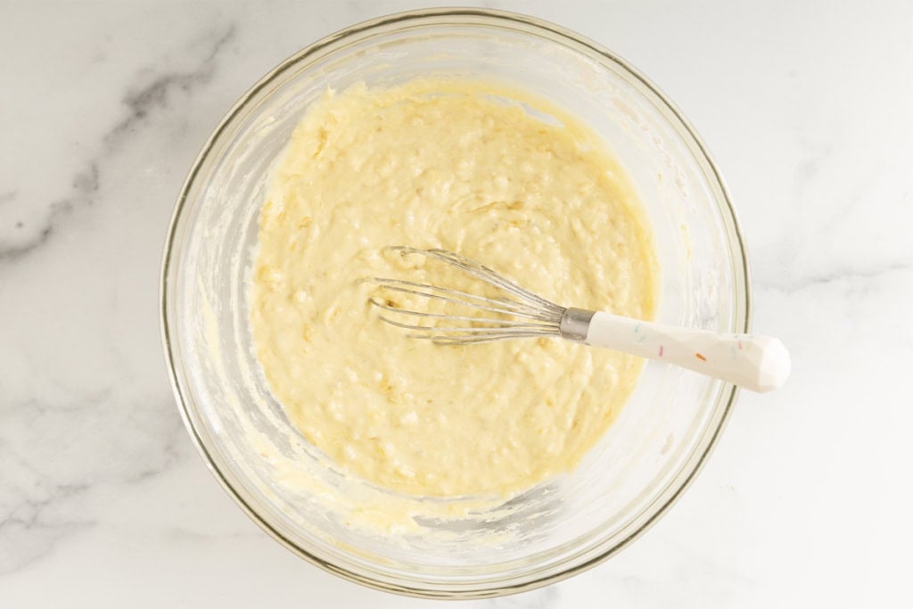 Batter for blueberry banana pancakes in glass bowl.