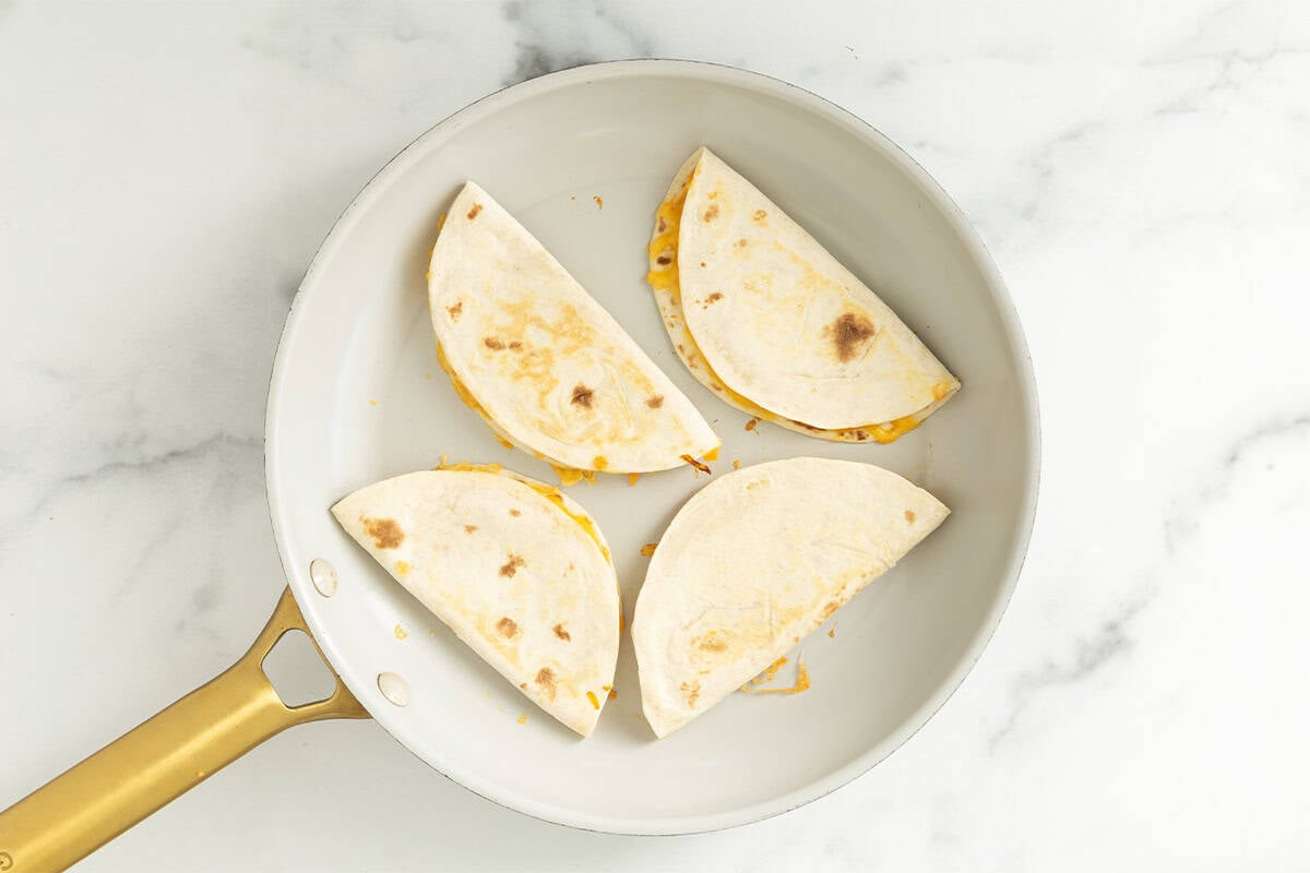 Cheese quesadillas in pan after flipping.
