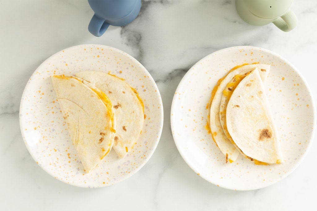 Cheese quesadillas on two white plates.