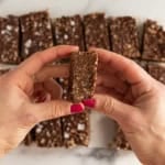 Hands holding chocolate crunch bar.