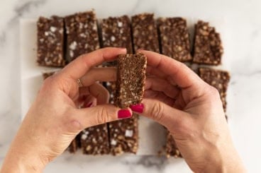 Hands holding chocolate crunch bar.
