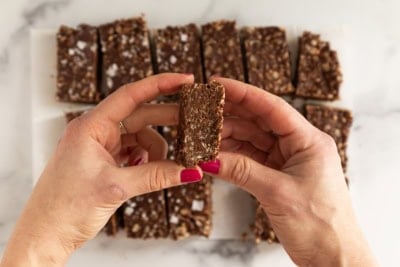 Hands holding chocolate crunch bar.