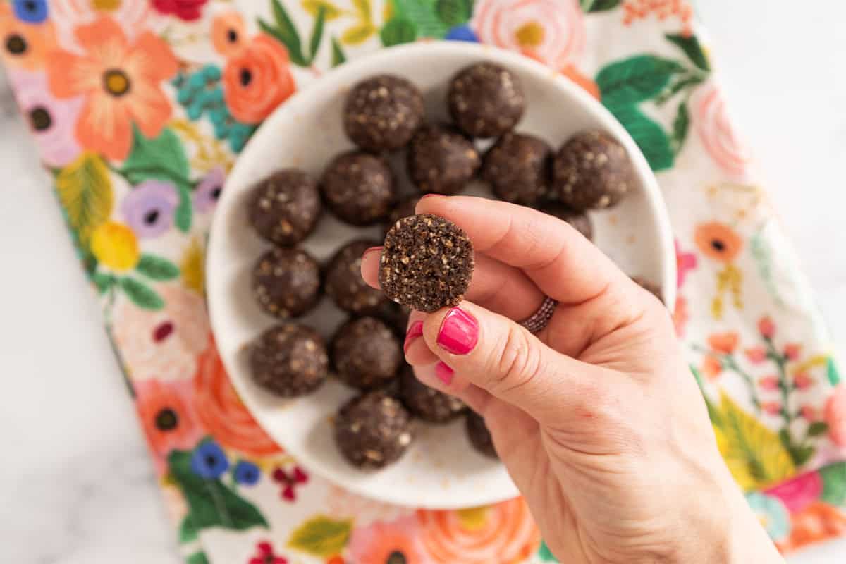 Hand holding chocolate date ball cut in half.