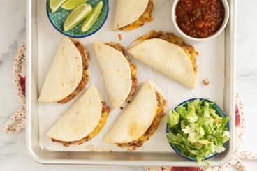 Mini tacos on baking sheet with sides.
