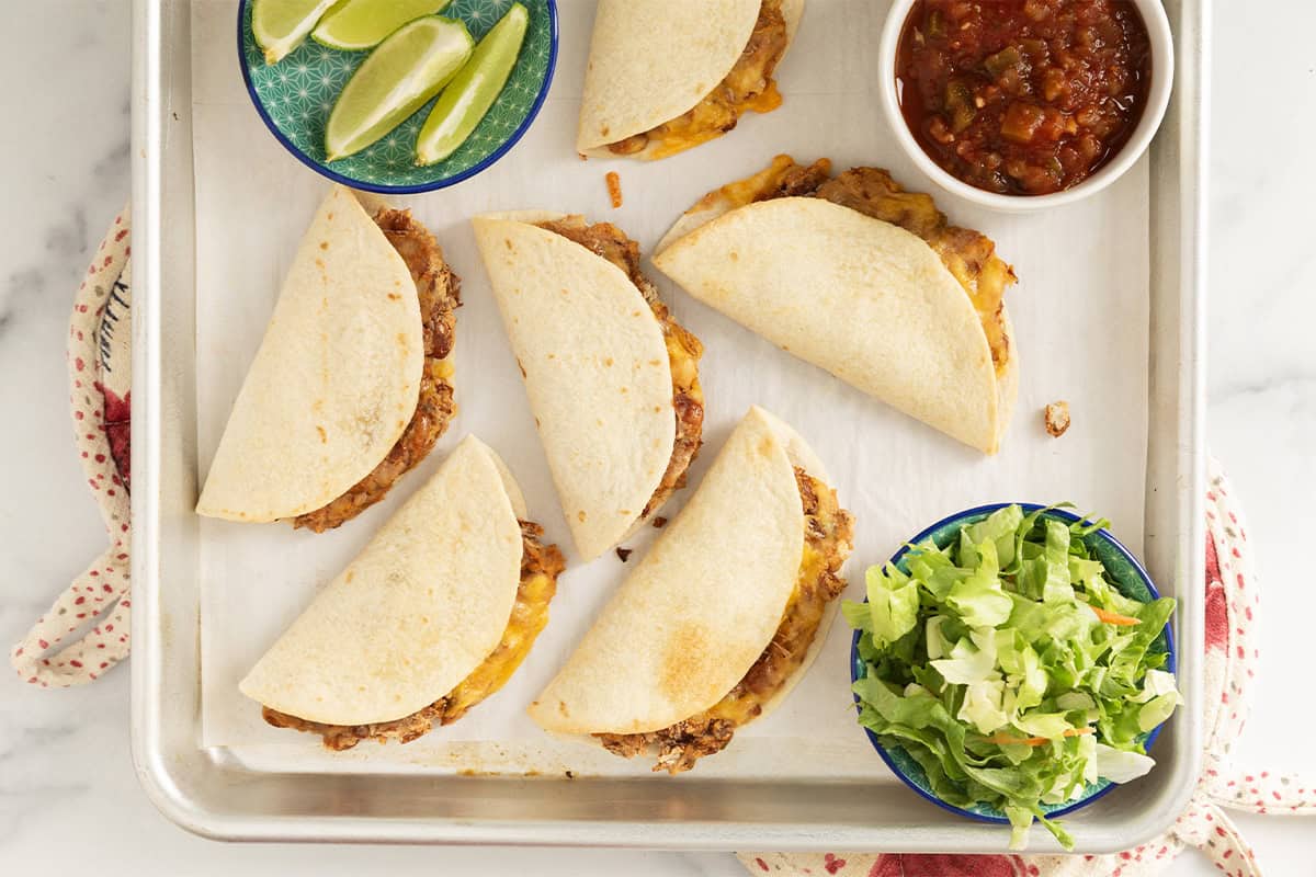 Mini tacos on baking sheet with sides.