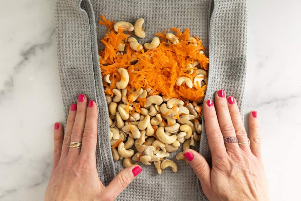Carrots and cashews in grey towel being dried for carrot balls.