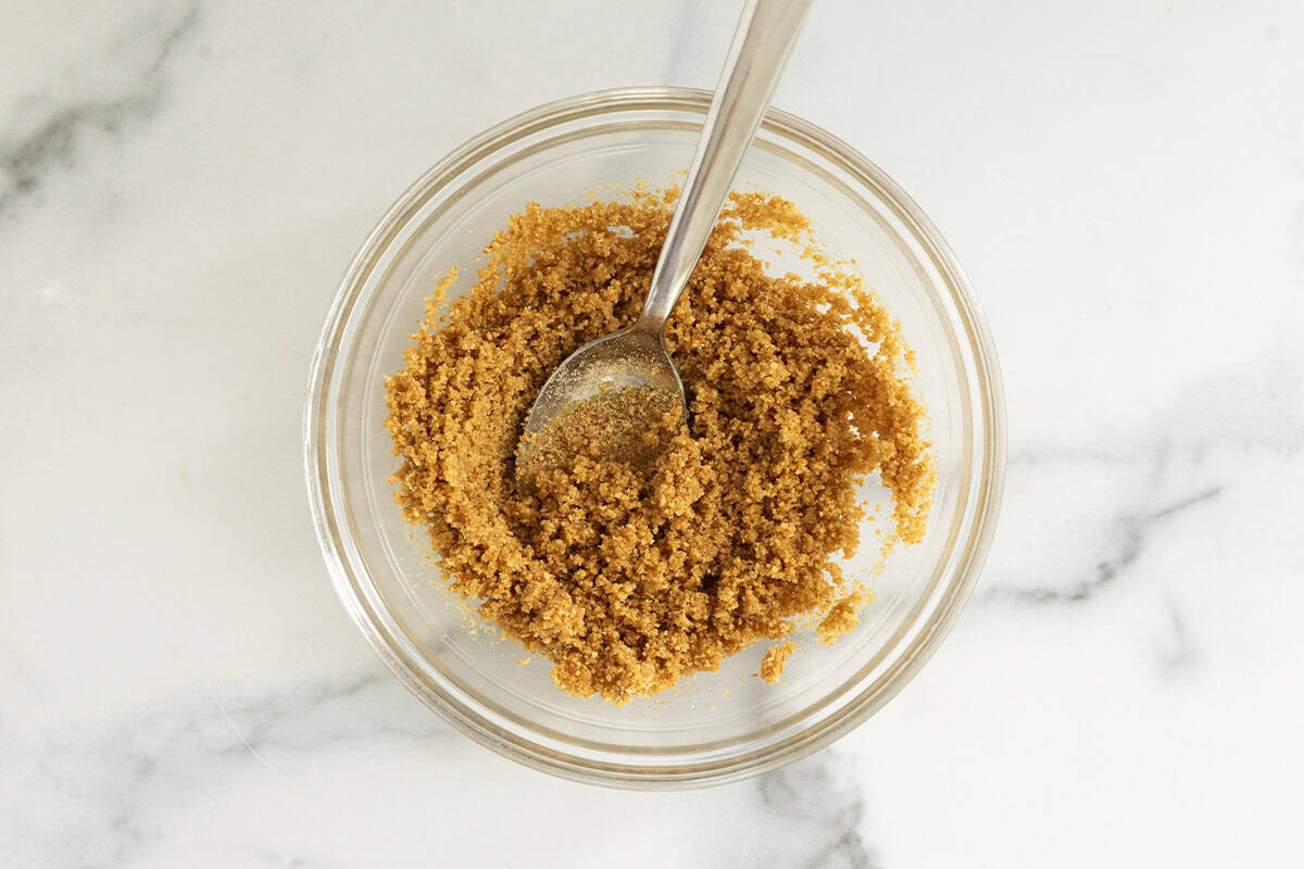 Crust ingredients for no bake strawberry cheesecake in glass bowl.