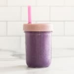 Blueberry milk in glass jar with lid and straw.