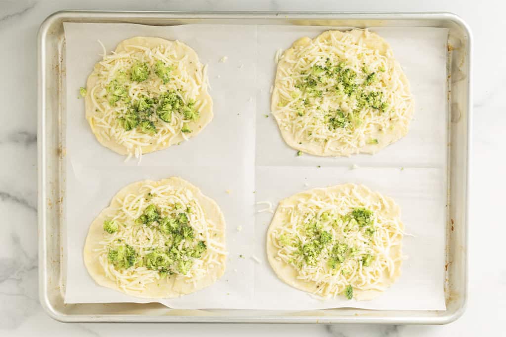 Broccoli and cheese on broccoli pizza before baking.
