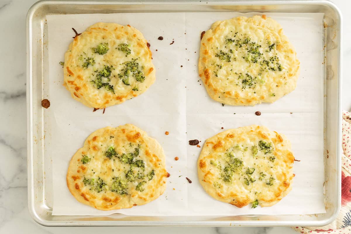 Broccoli pizza on baking sheet.