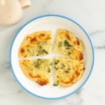 Broccoli pizza in four pieces on white plate.