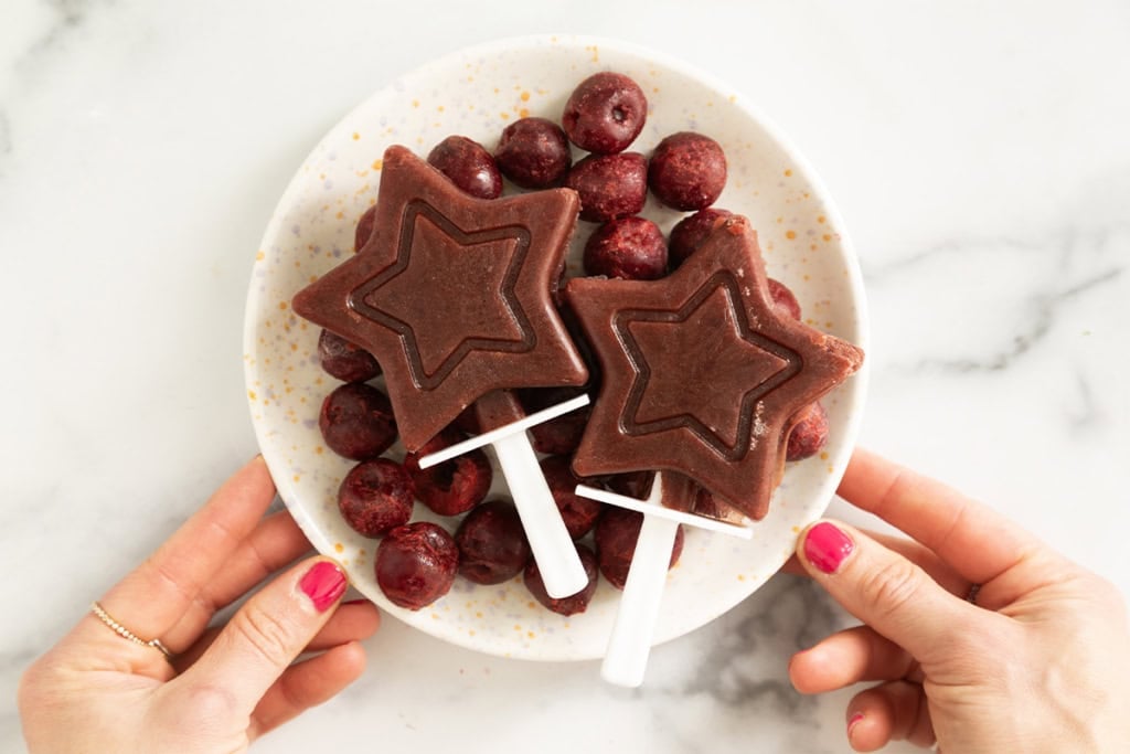 Cherry Popsicles on plate with hands holding plate.