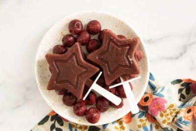 Cherry popsicles on white plate with cherries.