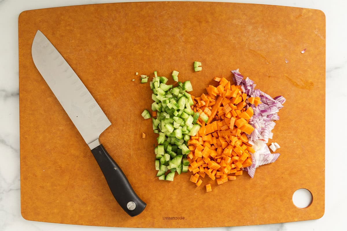 Veggies being chopped on cutting board for chicken mac salad.