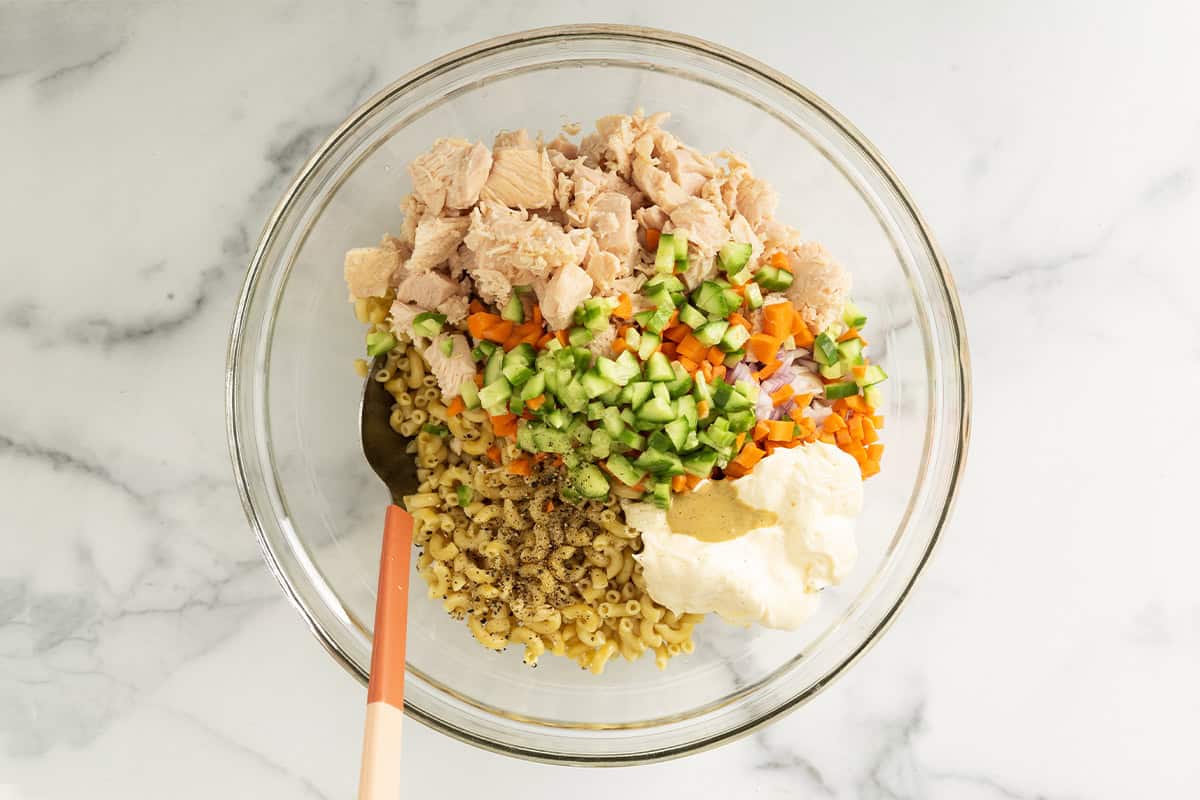 Ingredients for chicken mac salad in glass bowl before mixing.