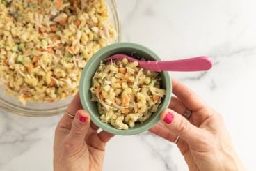 Chicken mac salad in blue bowl with pink spoon.