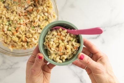 Chicken mac salad in blue bowl with pink spoon.