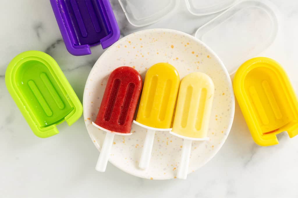 three frozen fruit bars on white plate.