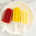 three frozen fruit bars on white plate.