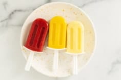 three frozen fruit bars on white plate.