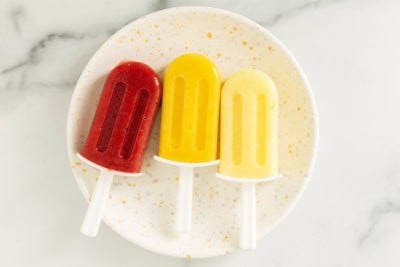 three frozen fruit bars on white plate.