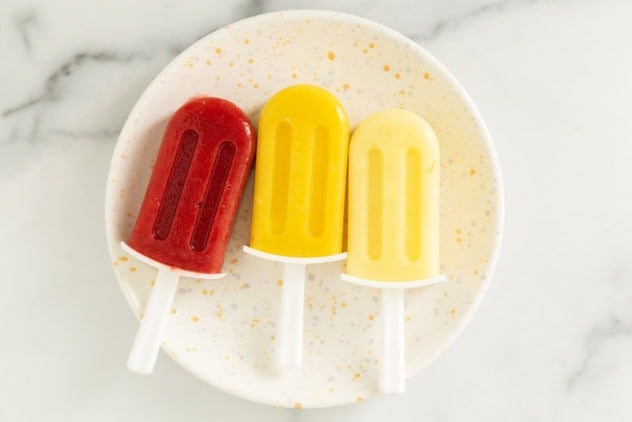 three frozen fruit bars on white plate.
