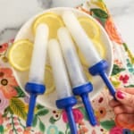 Lemon popsicles on white plate with lemons.