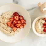 Two white bowls with overnight steel cut oats and strawberries.