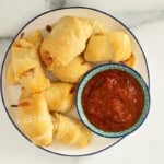 Pizza crescent rolls on white plate with dipping sauce.