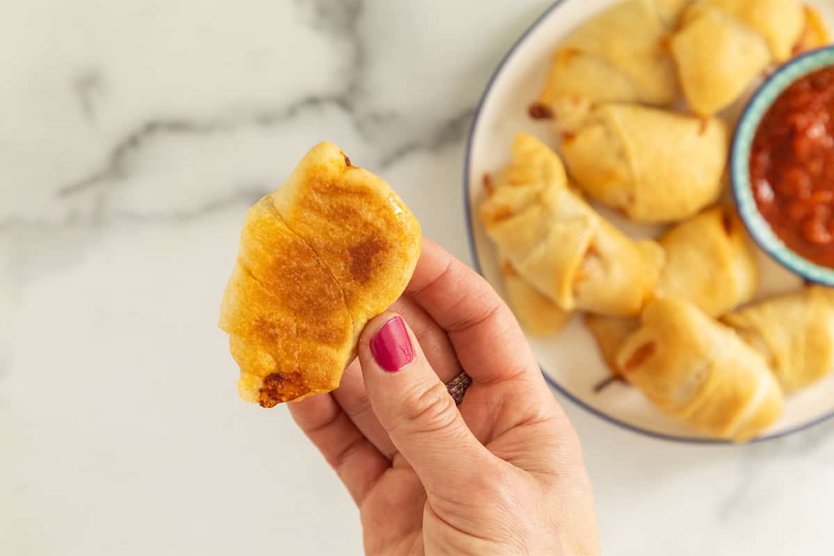Hand holding pizza crescent roll.