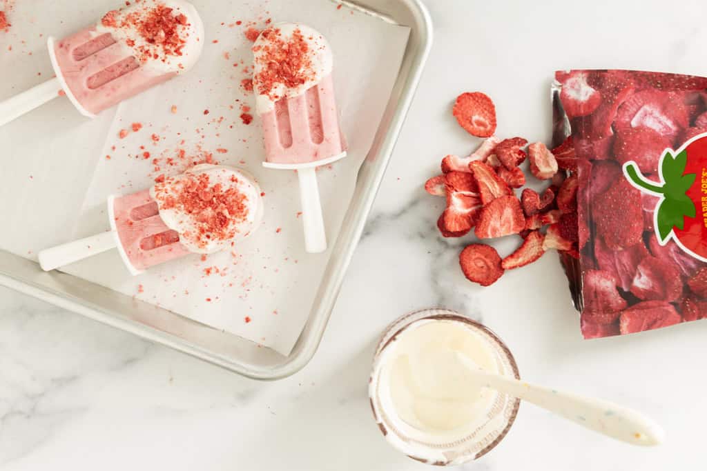 Adding dried strawberries to strawberry ice cream bars.