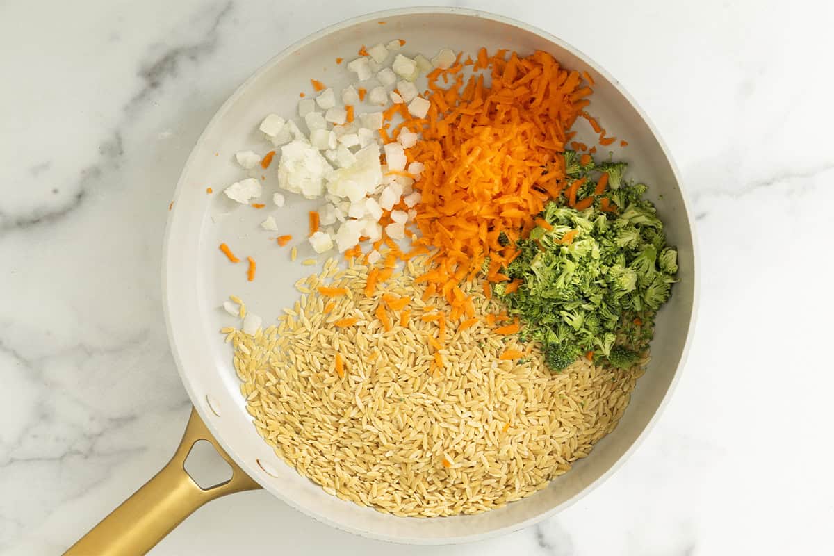 Chopped veggies and orzo in pan for veggie orzo.