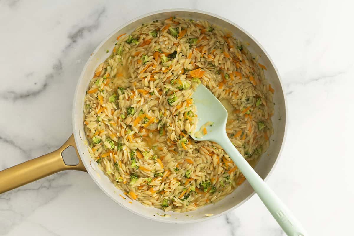 Veggie orzo in pan with spoon.