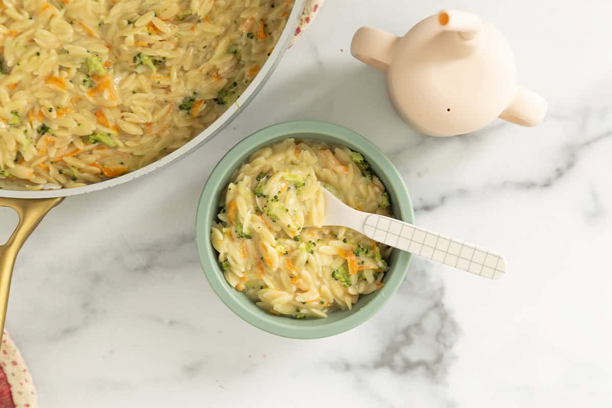 Veggie orzo in blue bowl with spoon.