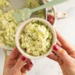 Hands holding bowl of zucchini rice.