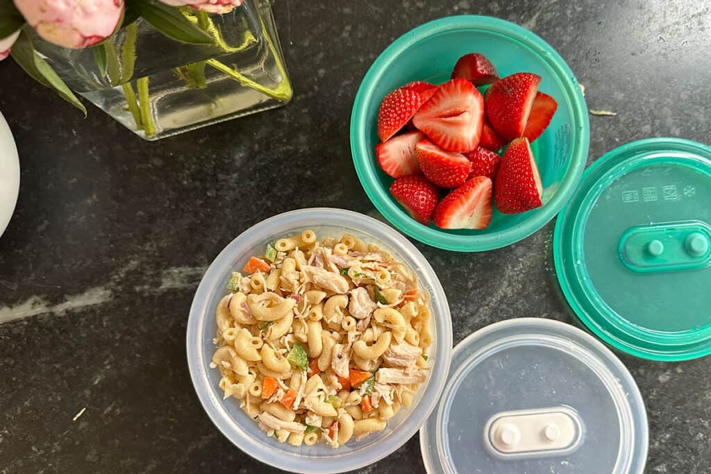 pasta salad and strawberries in silicone deli containers.