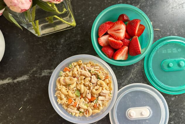 pasta salad and strawberries in containers.