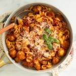 Chicken meatball pasta in pan with cheese and basil on top.