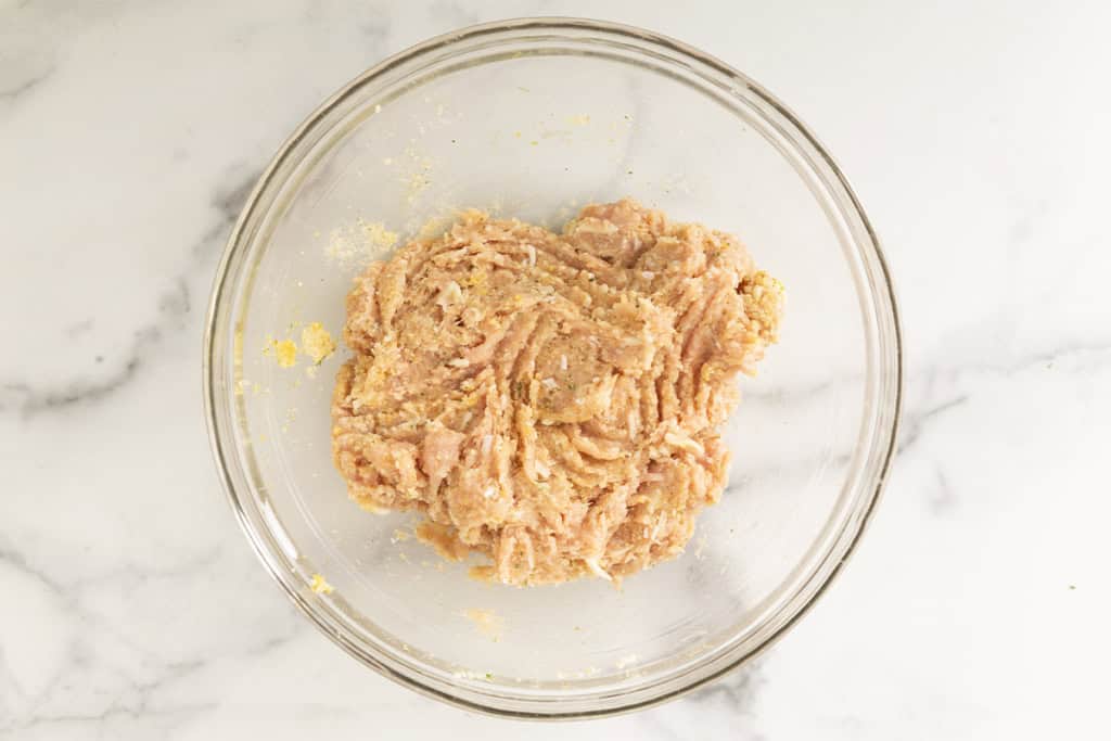 Mixture for chicken parmesan meatballs in glass bowl.